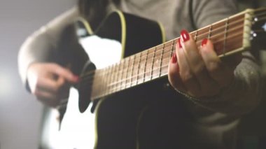 woman playing guitar, hands on strings close up
