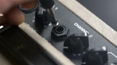 connecting a guitar to an amplifier, hands close-up