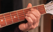 man playing guitar, hands on strings close-up