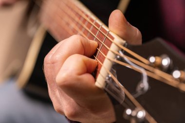 man playing guitar, hands on strings close-up