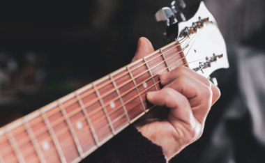 man playing guitar, hands on strings close-up