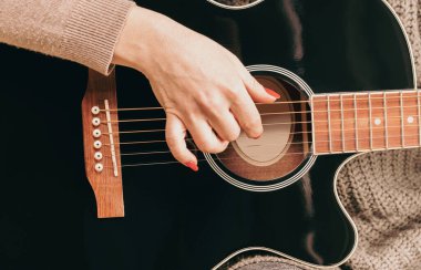 woman playing guitar, hands on strings close up