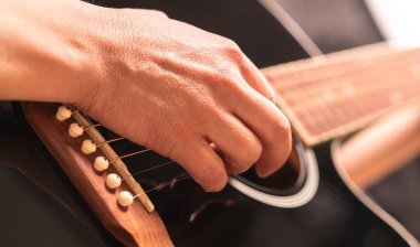 woman playing guitar, hands on strings close up