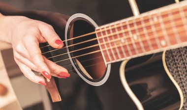 woman playing guitar, hands on strings close up