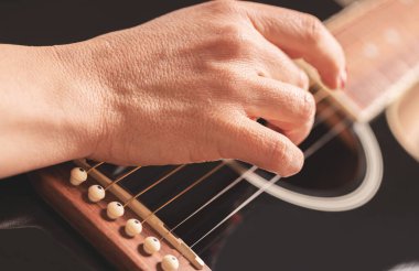 woman playing guitar, hands on strings close up