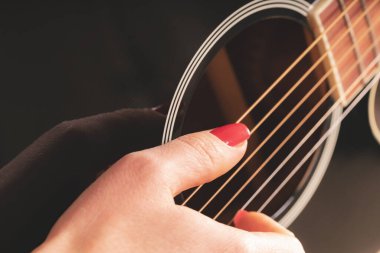 woman playing guitar, hands on strings close up