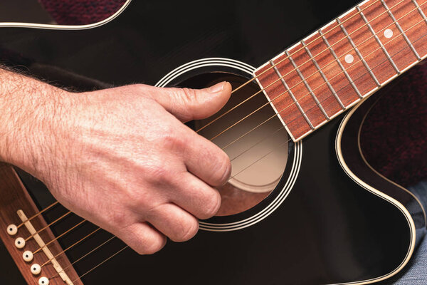 man playing guitar, hands on strings close-up