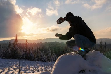 Ceketli genç adamı kapat ve güneş batarken termostan sıcak çay dök. Novohradske Dağı, Çek Cumhuriyeti