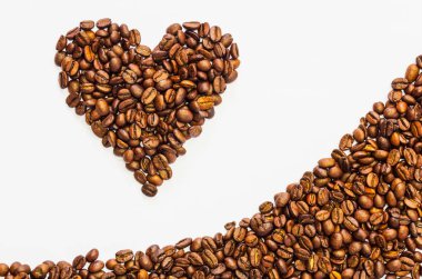 Kalp şeklinde ve kahveden yapılan dalgalar kavrulmuş fasulyeler beyaz arka planda izole edilmiş.