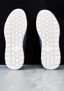 Sıradan erkek ayakkabısının lastik beyaz tabanı, siyah arka planlı mermer desenli çizmeler. Stüdyo fotoğrafı