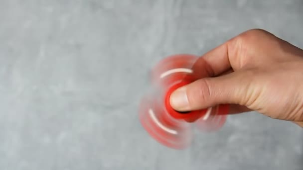 大理石の背景に赤いプラスチック製のフィジェットスピナーを回転男の手 ストレス対策玩具 — ストック動画