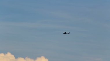 Black small helicopter flying on blue sky