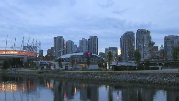 Vancouver bc british columbia Kanada med vacker utsikt över kontor bostadsrättslägenhet byggnader moln och rörliga båtar längs false creek på blå timmen i natt tid förflutit 1080p — Stockvideo