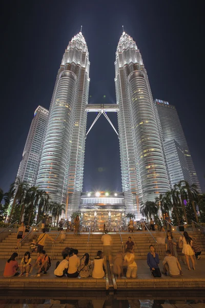 Touristes par Petronas Twin Towers la nuit — Photo