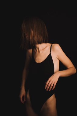 Yerde soyut pozlar, klasik beden kıyafetli bir kız sezgisel olarak siyah arka planda dans ediyor, bulanık fotoğraflar ve bulanık resimler, resim sesleri, odaklanmamış tam boy portreler.