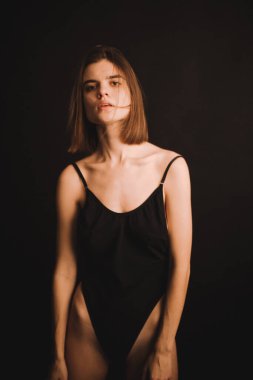 Yerde soyut pozlar, klasik beden kıyafetli bir kız sezgisel olarak siyah arka planda dans ediyor, bulanık fotoğraflar ve bulanık resimler, resim sesleri, odaklanmamış tam boy portreler.