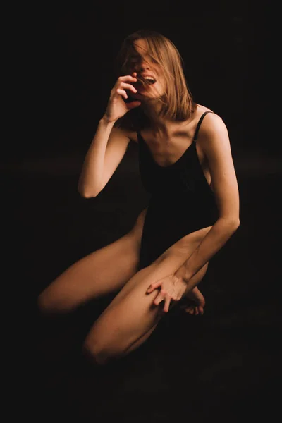 床に抽象的なポーズ 黒い背景で直感的に踊る古典的なボディスーツの少女 ファジィな写真とぼやけ アートイメージのノイズ 焦点を当てられていない全長の肖像画 — ストック写真