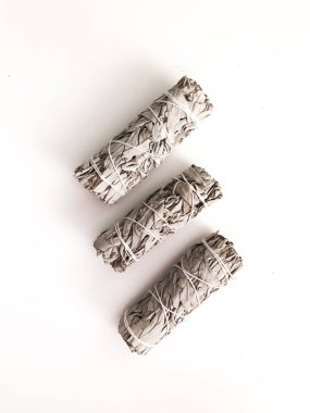 Yakından bir demet kuru beyaz adaçayı. Arındırma, meditasyon ve iyileştirme için ürün. Tesisleri dezenfekte etmek için tütsü. Beyaz arka planda beyaz adaçayı dalları. Yukarıdan görüntüle.