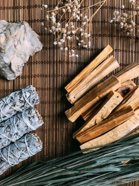 Bambu kahverengi bir standın üzerinde tütsü, Peru ve Kaliforniya 'dan palo santo, etraftaki kurumuş çiçekler. Doğal tütsü ve ışık arkaplan bulanıklığına sahip metin için sanat arkaplanı