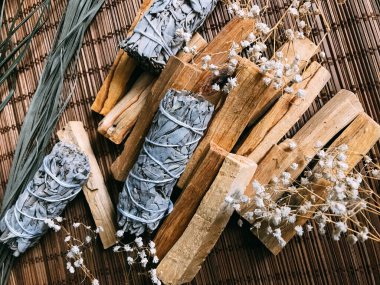 Bambu kahverengi bir standın üzerinde tütsü, Peru ve Kaliforniya 'dan palo santo, etraftaki kurumuş çiçekler. Doğal tütsü ve ışık arkaplan bulanıklığına sahip metin için sanat arkaplanı
