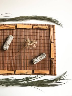 Bambu kahverengi bir standın üzerinde tütsü, Peru ve Kaliforniya 'dan palo santo, etraftaki kurumuş çiçekler. Doğal tütsü ve ışık arkaplan bulanıklığına sahip metin için sanat arkaplanı
