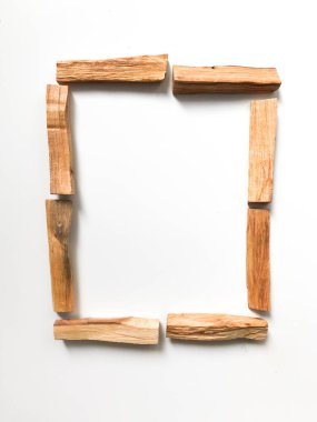 Ahşap palo santo sopalarının, aromaterapinin ve beyaz arka plandaki aromaların büyüsünün çok güzel bir arka planı var. Işık görüntüsü bulanıklaşması, odak eksikliği, yumuşak doku kombinasyonları.