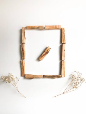 Ahşap palo santo sopalarının, aromaterapinin ve beyaz arka plandaki aromaların büyüsünün çok güzel bir arka planı var. Işık görüntüsü bulanıklaşması, odak eksikliği, yumuşak doku kombinasyonları.