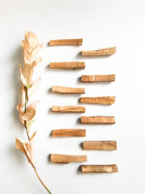 Ahşap palo santo sopalarının, aromaterapinin ve beyaz arka plandaki aromaların büyüsünün çok güzel bir arka planı var. Işık görüntüsü bulanıklaşması, odak eksikliği, yumuşak doku kombinasyonları.