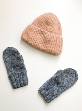 Beyaz arka planda sıcak kış eldivenleri ve boneler. Estetik minimalist kavram. Düz yatıyordu, üst görünüm moda kalıpları