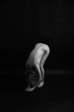 Athletic nude woman body on dark background. Fine-art photo of nude woman body.