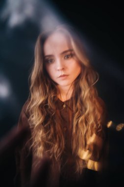 Avrupa Slav görünümlü ve kahverengi saçlı genç bir kız, bej rengi bir kimyevi elbise, kayışlı bir elbise, kameraya neşeyle bakıyor, oyunculuk yetenekleri ve yüzünde basit yüz ifadeleri, açık bir şekilde 