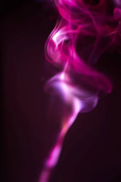 담배와 담뱃불에서 나오는 분홍빛 진홍색 연기가 마법의 세계를 — 스톡 사진