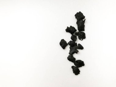 Beyaz arka planda koyu tütsü reçinesi, küçük reçine parçalarının aroması.