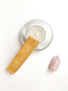 Palo santo tütsü çubuğu meditasyon için, mum ve gül kuvars kristali beyaz arka planda, metin için yer, üst görünüm için