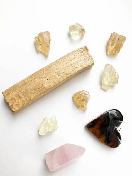Set of palo santo sticks, rose quartz crystal and natural incense and dammar resins, close-up on a white background, place for text, altar layout