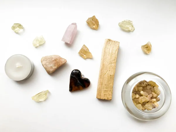 Set of palo santo sticks, rose quartz crystal and natural incense and dammar resins, close-up on a white background, place for text, altar layout