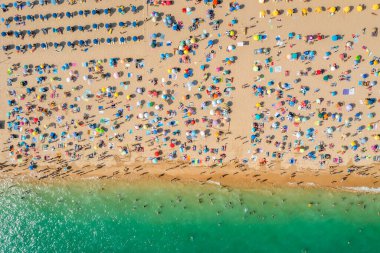 Birçok insanın deniz ve kumsalın tadını çıkardığı insansız hava aracı görüntüleri. Tatil modelleri. Portekiz, Portimao 'daki Rocha Plajı