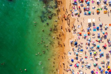 Birçok insanın deniz ve kumsalın tadını çıkardığı insansız hava aracı görüntüleri. Tatil modelleri. Portekiz, Portimao 'daki Rocha Plajı