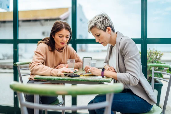 Dwie Kobiety Rozmawiające Pokazujące Coś Przez Telefon Kawiarni Dworcu Kolejowym — Zdjęcie stockowe