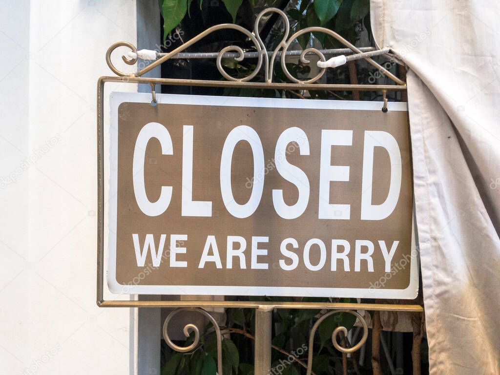 Metal sign saying: Closed. We are sorry. On brown background.