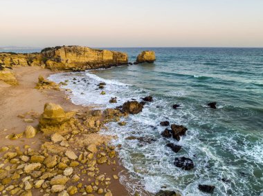 Günbatımında Atlantik Okyanusu kıyısındaki Sao Rafael sahilindeki uçurumların havadan görünüşü, Algarve, Portekiz