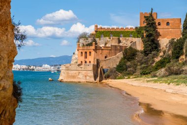 Kumlu sahil şeridi ve Ferragudo, Algarve, Portekiz 'deki Sao Joao kalesi.