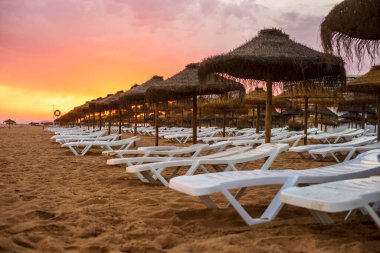 Vilamoura, Algarve, Portekiz 'de güneş yatakları ve şemsiyeler üzerinde güzel renkli gün batımı