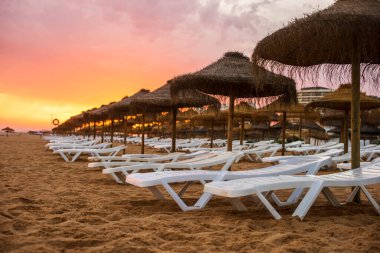 Vilamoura, Algarve, Portekiz 'de güneş yatakları ve şemsiyeler üzerinde güzel renkli gün batımı