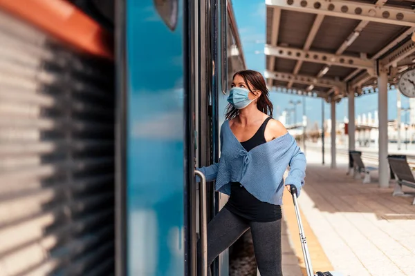 荷物を持って電車に乗る保護マスクの若い女性 — ストック写真