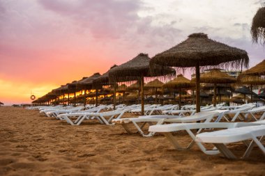 Vilamoura, Algarve, Portekiz 'de güneş yatakları ve şemsiyeler üzerinde güzel renkli gün batımı