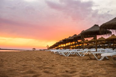Vilamoura, Algarve, Portekiz 'de güneş yatakları ve şemsiyeler üzerinde güzel renkli gün batımı