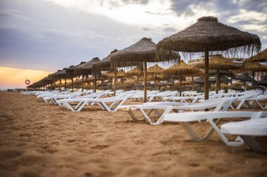 Vilamoura, Algarve, Portekiz 'de güneş yatakları ve şemsiyeler üzerinde güzel renkli gün batımı