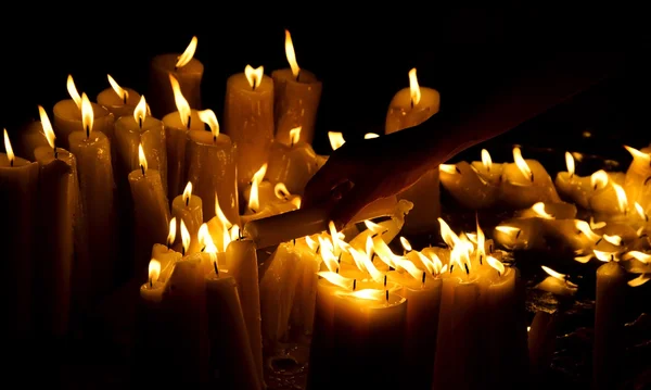 Menselijke hand verlichting kaars in de kerk — Stockfoto