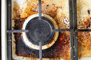 Kirli gaz sobası yüzeyi. Büyük bir gaz ocağı ve eski yiyecek ve içeceklerle çevrili bir gaz fırınının demir ızgarası. Üst bölge yüzeyi ve kullan-at kafaların yanmış yağlardan temizlenmesi gerekiyor.
